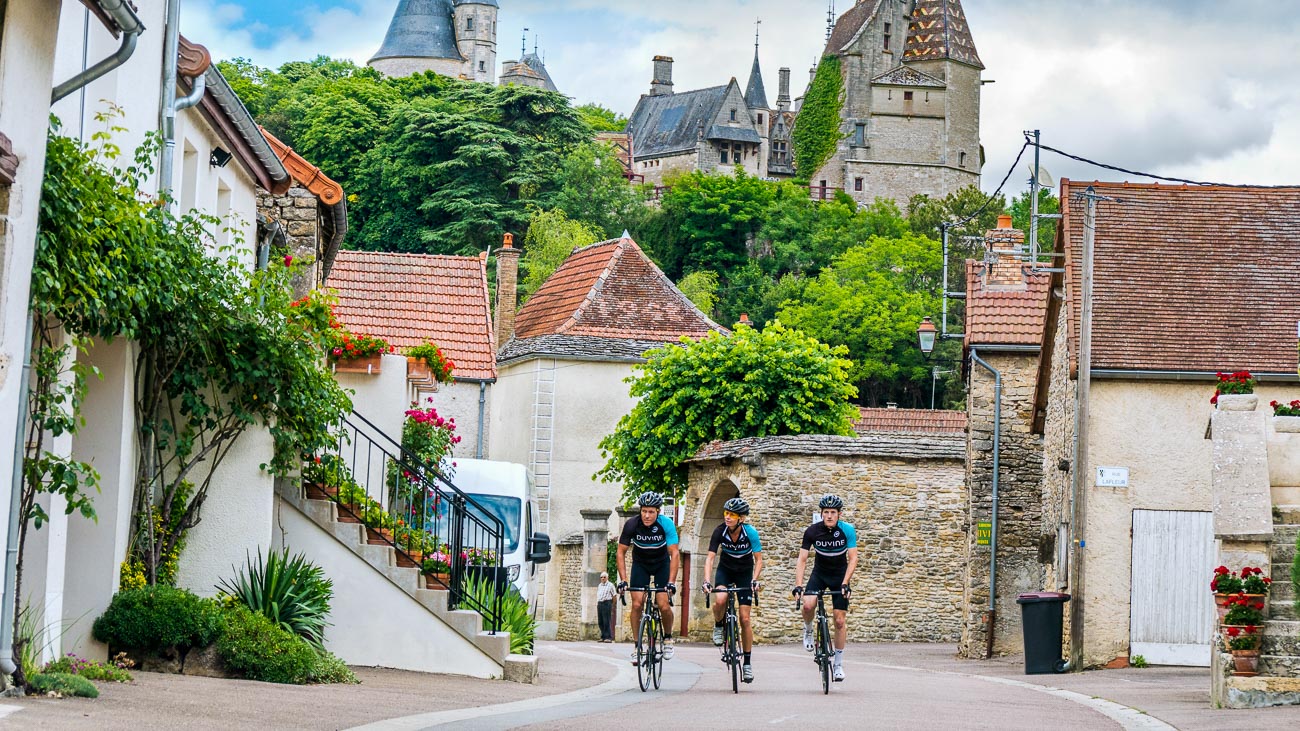 A trio of cyclists in DuVine kits biking through a village in Burgundy, France