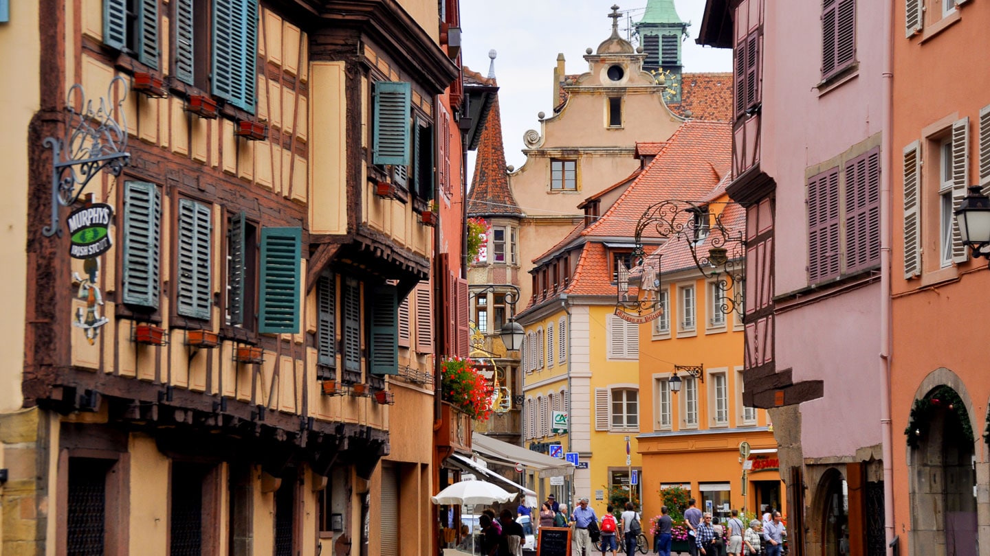Village with traditional Alsatian architecture and pedestrians in Alsace, France