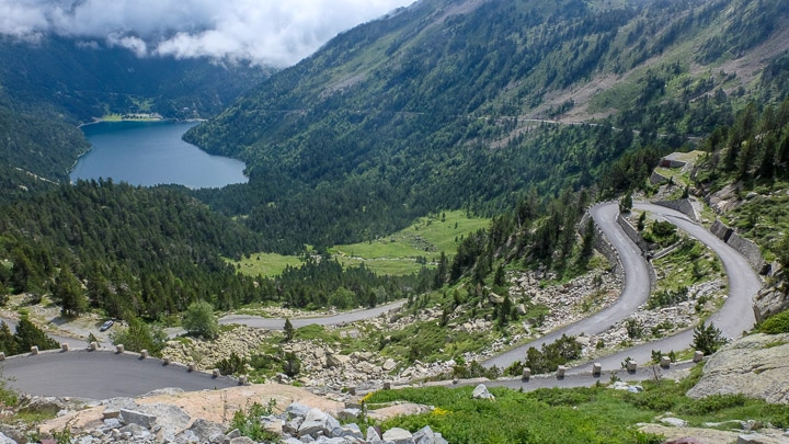 The Col du Peyresourde with a winding road, mountains, forests, and a lake in the distance in the Pyrenees, France
