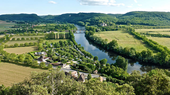 An aerial landscape of green fields and trees bisected by a river in the Dordogne