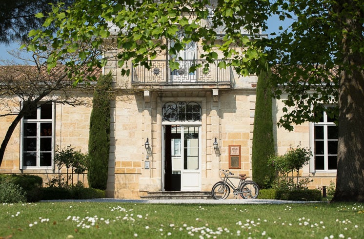 Front garden and main entrance of Château Cordeillan-Bages hotel with bikes