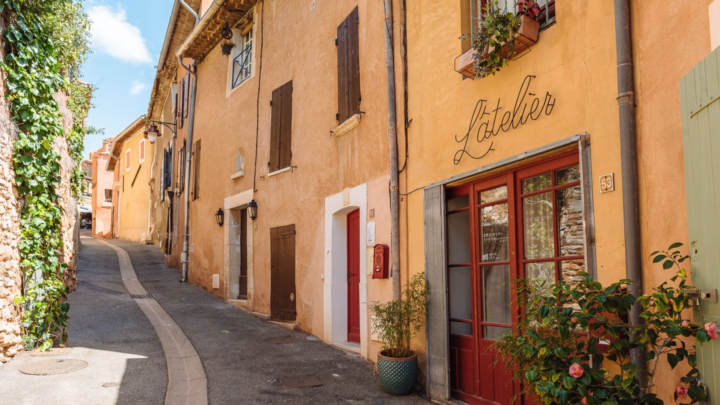 Narrow street in the Provençal village of Rousillon, France, with red-orange buildings